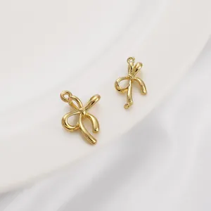 Dettaglio macro di ciondoli a fiocco placcati oro 14K su sfondo di seta bianca