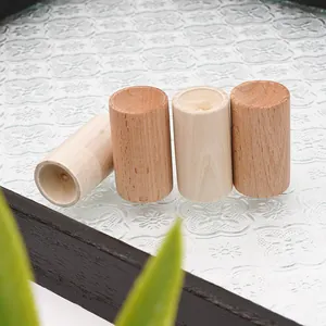 Detalle de cuatro difusores de aceites esenciales de madera cilíndricos en bandeja de vidrio