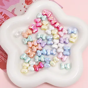 Iridescent bow beads in pastel colors for DIY jewelry making on white star tray