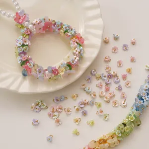 Macro shot of lily of the valley resin flower charms in pastel colors with gold accents