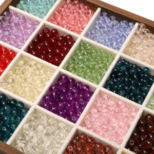 Multi-colored transparent glass beads organized in a wooden divider box for DIY jewelry