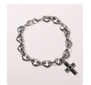 Détail de la chaîne à cœurs en acier avec pendentif croix strass noir et fermoir mousqueton