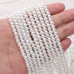 Dettaglio macro di perle di vetro bianche da 3-5 mm in mano per gioielli fai da te