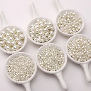 Perle di vetro bianche in sei dimensioni su piatti di ceramica per creazione di gioielli fai da te