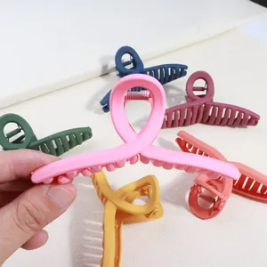 Large matte cross hair claw clips in six colors held by hand for size reference