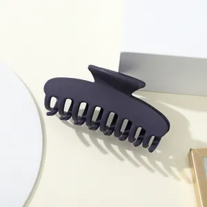 Grande pinza per capelli blu scuro opaco mostrata con eleganti oggetti geometrici