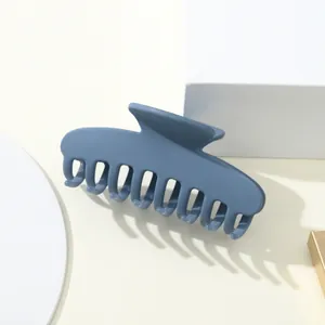 Dettaglio macro della grande molletta blu opaco con denti arrotondati per capelli lunghi