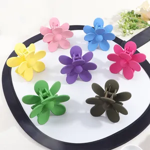 Matte flower hair claw clips in seven candy colors shown on a white decorative plate