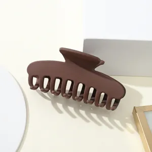 Dettaglio di una grande pinza per capelli marrone opaco con denti intrecciati su bianco