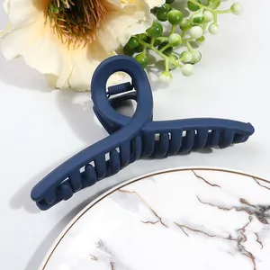 Detail of large matte navy blue cross hair claw clip with spring on marble plate
