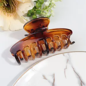 Detail view of large amber leopard print hair claw clip on an elegant marble plate