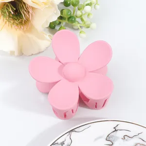 Detail of pink matte flower hair claw clip with interlocking teeth on marble surface