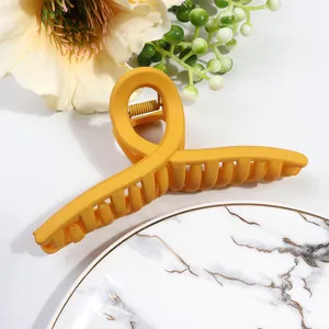 Detail of large matte ginger yellow hair claw clip with crossed teeth design for women