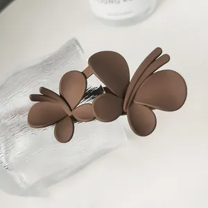 Close-up of matte brown double butterfly hair claw clip with frosted texture and elegant design