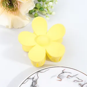 Detailed macro shot of yellow matte flower hair claw clip on marble decorative plate