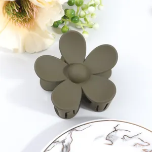 Close-up of olive green matte flower hair claw clip with marble tray decor