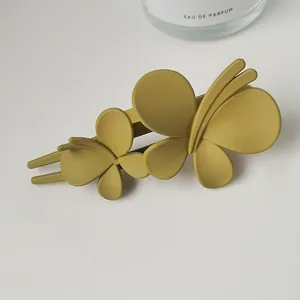 Detail of a matte mustard yellow butterfly hair clip with double-layered 3D wings