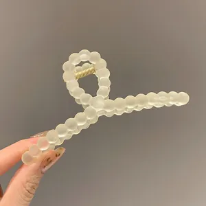 Detail of matte white macaron beaded hair claw clip with strong golden metal spring