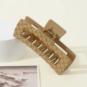 Detail van een grote kaki haarklem met een mat ruitpatroon en sterke metalen veerstructuur