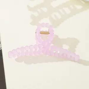 Macro view of purple matte beaded hair claw clip with golden metal spring detail