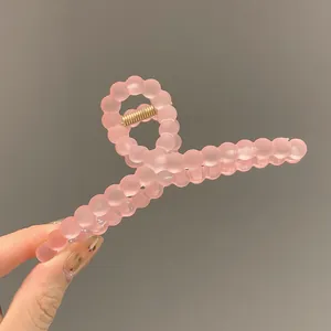 Macro view of matte pink bubble bead hair claw clip with golden metal spring