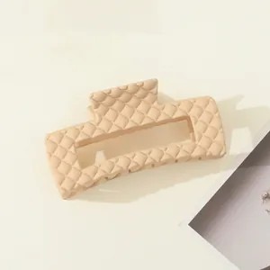 Detail van grote beige haarklem met gewatteerd ruitpatroon en een matte afwerking