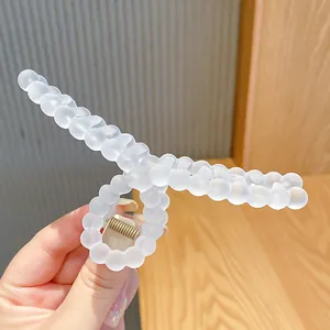 Close-up of a matte white hair claw clip with a unique beaded texture and metal spring