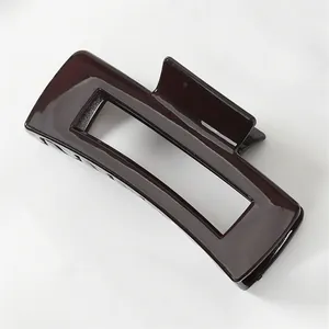 Close-up of a glossy dark brown rectangular claw clip with a sleek hollow-out design