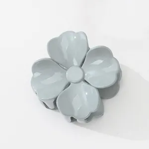 Detailansicht einer glänzenden Haarspange in Blumenform in einem dezenten Graublau-Ton