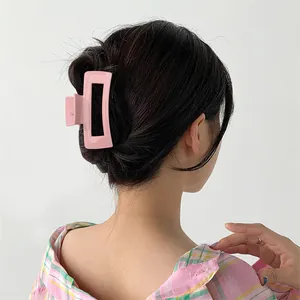 Glossy pink macaron shark clip for thick hair styling on a female model's bun