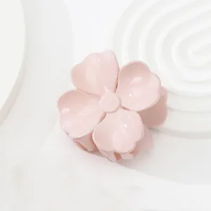 Nahaufnahme einer hellrosa Haarspange in Blumenform auf weißem minimalistischem Grund