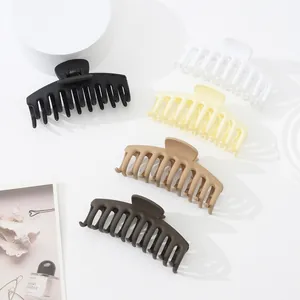 Lot de grandes pinces à cheveux mates aux tons neutres sur des supports blancs minimalistes