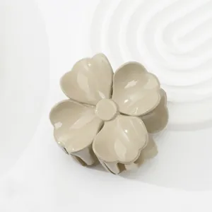 Glänzende cremefarbene Blumen-Haarklammer auf einem minimalistischen weißen Sockel