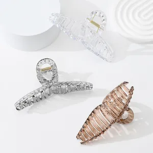 Diamond-cut acrylic hair clips in clear, grey and amber on white minimalist pillars