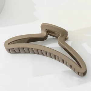Detalle de una pinza para el pelo color caqui mate con textura esmerilada y muelle metálico