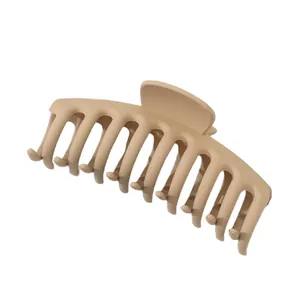 Vue détaillée d'une pince à cheveux mate beige avec de grandes dents en forme d'os