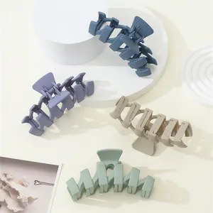 Detail of four matte textured wave hair claws in navy, mauve, beige and green