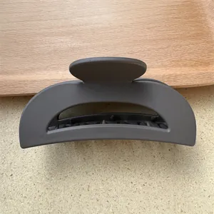 Vista dettagliata della grande pinza per capelli grigio opaco su vassoio in legno