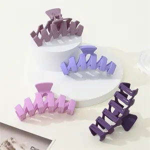 Detailed view of four matte purple wavy hair claws on white geometric display stands