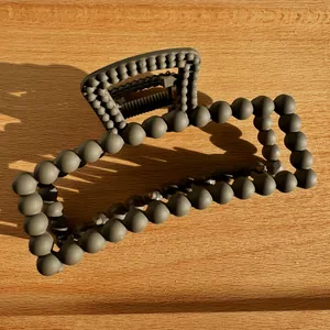 Macro shot of matte grey rectangular claw clip with unique 3D spherical bead textures