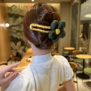 Detail einer dunkelgrünen Stoffblumen-Haarklammer auf einer eleganten braunen Hochsteckfrisur