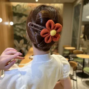 Detail einer Wollfilz-Blüten-Haarklammer in Orange und Gelb an einem Haarknoten