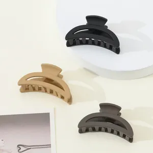 Three matte mini claw clips in black, beige, and grey on a clean white display stand