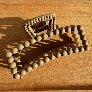Close-up of khaki matte bubble hair claw clip with rectangle hollow design on wood board