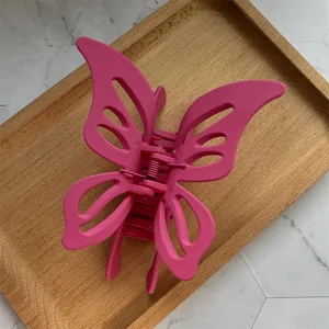 Macro view of large matte hot pink butterfly claw clip with hollow wings and metal spring