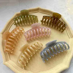 Top view of six assorted jelly colored resin hair claws on an octagonal matte tray