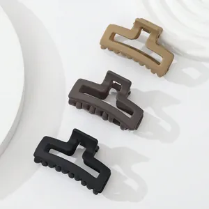 Detailed macro of three matte geometric hair claws in beige, brown, and black colors