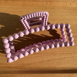 Matte taro purple hair claw clip with ball texture and rectangular frame on wood surface