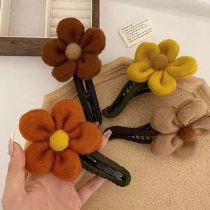 Detail von vier Blumen-Haarklammern aus Plüsch in warmen Farben mit weichen Filz-Blütenblättern