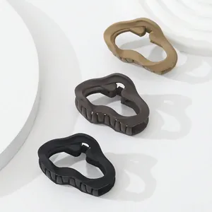 Close-up of three matte hair claws in brown and black with wavy geometric design